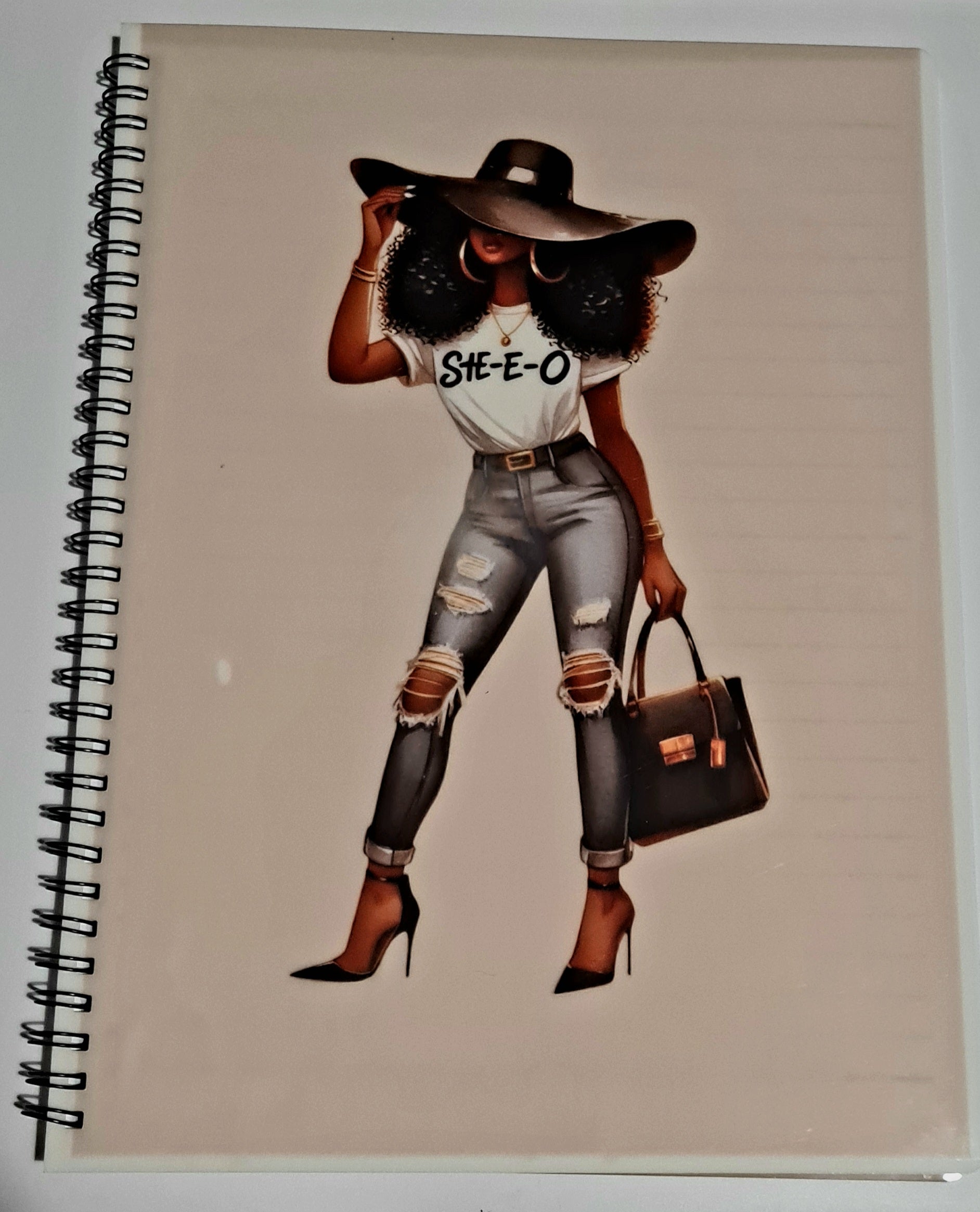 Notebook with a stylish illustration of a black woman on the cover, her tshirt says She-e-o